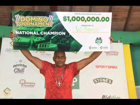 Wilfred Barnes, the champion of the inaugural Supreme Domino Masters Series, proudly displays his well-deserved $1 million cheque on Sunday at the Chinese Benevolent Association headquarters on Old Hope Road.