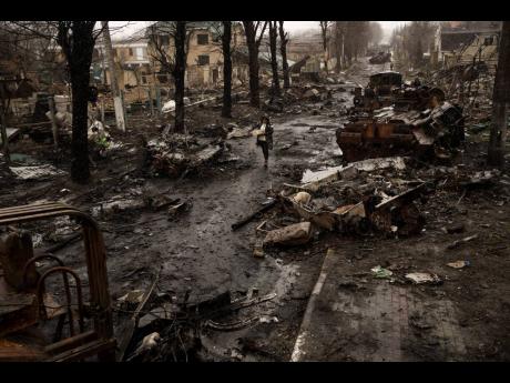 A woman walks amid destroyed Russian tanks in Bucha, in the outskirts of Kyiv, Ukraine, on April 3, 2022.