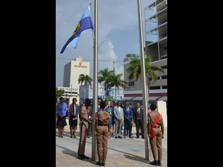 Government ministers and members of the Opposition watch as the Jamaican flag and the CARICOM flag are hoisted at the Ministry of Foreign Affairs and Foreign Trade by members of the Jamaica Combine Cadet Corp on Thursday. The ceremony was to mark the Treat