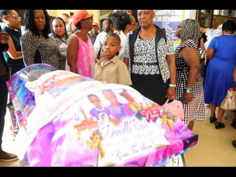 People try to view the body of Danielle Rowe, but a shirt with paint, depicting blood, on a picture of Danielle was placed over the coffin.