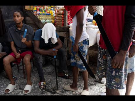 Men with machetes, part of ‘Bwa Kale’, an initiative to resist gangs from getting control of their neighbourhood, hold their machetes in the Delma district of Port-au-Prince, Haiti, on May 28.