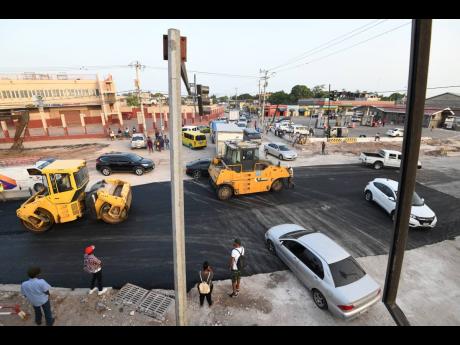 Operators of rollers compress asphalt at a section of Hagley Park Road in July 2019.