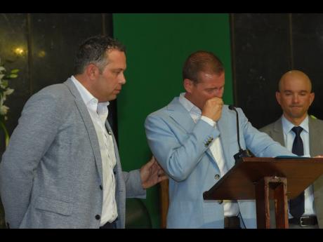 An emotional Adam Stewart (centre), executive chairman of Sandals Resorts International, is consoled by Yoni Epstein, chairman and CEO of intelCX, as Jordan Samuda, chief administrative officer, Sandals Resorts International, looks on.