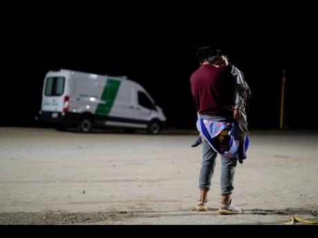 A man from Colombia holds his son as he waits to apply for asylum after crossing the border from Mexico.