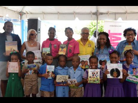 Children from schools across western Jamaica display books they received during the Blue World Travel Corp Festival At Sea children’s book donation ceremony at the Montego Bay Cruise Port in St James on July 28. Sharing the moment are (back row) Visitor 