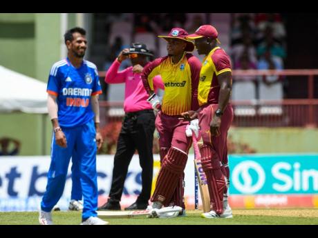 West Indies captain Rovman Powell, stops to talk with teammate Shimron Hetmyer (centre) during the third T20 International between the teams in Georgetown, Guyana yesterday.