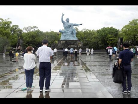 Visitors offer silent prayers for the victims of US atomic bombing in front of the Peace Statue in Nagasaki, southern Japan, on Wednesday, August 9.