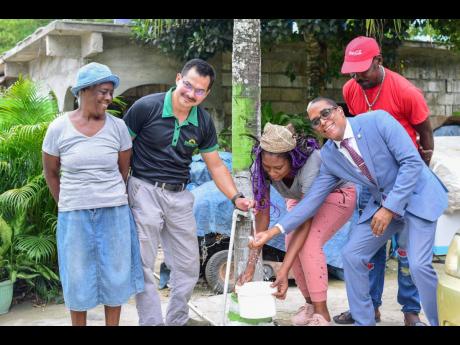 Gray’s Inn community residents Joyce Lawrence (left), Vivine Pickersgill (third right) and Calvin Shakes (standing behind), rejoice alongside JP Farms General Manager Mario Figueroa (second left) and Member of Parliament for South East St Mary Dr Norman 