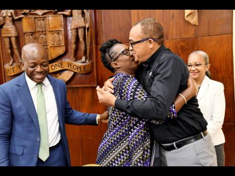 Credit: Rudolph Brown Christine Hendricks, executive director of the Jamaica Council for Persons with Disabilities, hugs Dr Christopher Tufton, Minister of Health and Wellness while Pearnel Charles Jr, (left) Minister of Labour and Social Security and Colette Roberts Risden (ri