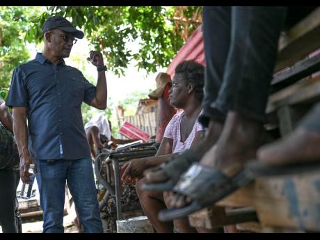 Credit: Ricardo Makyn Senator Peter Bunting, representing the People’s National Party, during a tour of a section of Walkers Avenue in Gregory Park, St Catherine, yesterday, speaks with a resident where a number of families were recently burnt out by gang members.