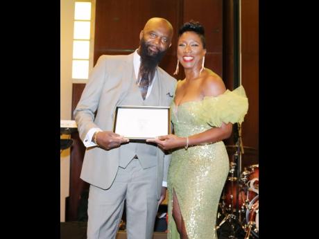 Leopold Gordon accepts the 2023 Vin Martin Community award from senior director in the Office of Public and International Affairs, Hartsfield-Jackson Atlanta International Airport, Alrene Barr, at the Atlanta Jamaica Association (AJA) Annual Independence B