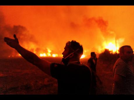 People react as they try to extinguish a wildfire in Avantas village, near Alexandroupolis town, in the northeastern Evros region, Greece, on Monday.