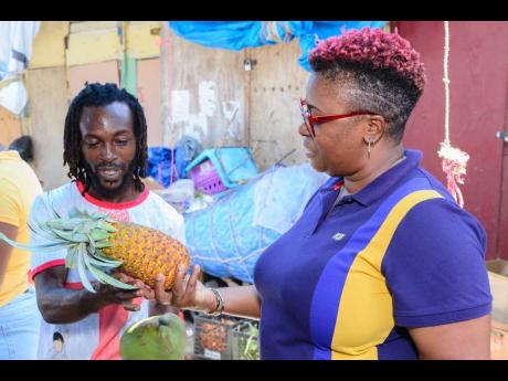 Anthony Tyrell, father of two and vendor for over 15 years, shares a friendly smile with Kayon Morrison, branch manager for NCB Port Antonio, as she purchases local produce outside the fire-ravaged Musgrave Market. Tyrell is one of over 200 vendors displac