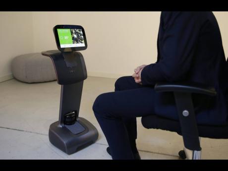 In this November 30, 2017, photo, CEO Yossi Wolf hears from Temi ‘personal assistant’ robot what the weather is in London during an event in San Francisco.