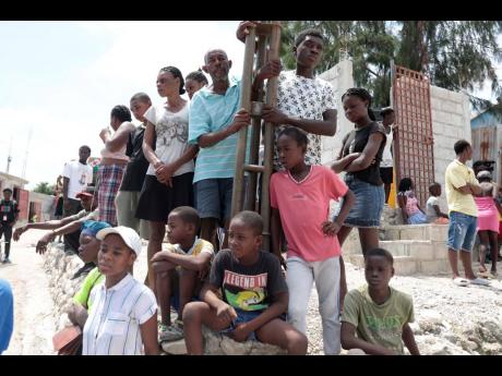 Locals stand around after people were killed during a religious march against a criminal gang in Canaan at Tabare, in the district of Port-au-Prince, Haiti, on Sunday, August 27. The powerful gang opened fire on the large group of parishioners as they marc