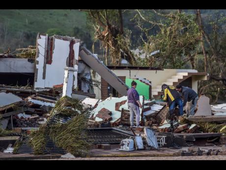 Marcos Gomes (second right) searches for belongings at the site of his destroyed home after floods caused by a cyclone in Mucum, Rio Grande do Sul state, Brazil, on Wednesday. 