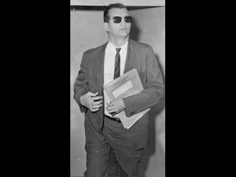Then Minister of Finance, Development and Welfare, Edward Seaga, with the 1967/68 budget in hand ascends the steps of Gordon House to present the budget  in a suit and tie. 