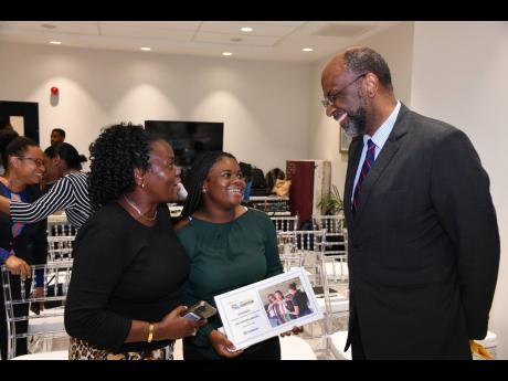 Earl Jarrett, chief executive officer of The Jamaica National Group, congratulates Kodia Allen (centre) , winner of the Greatness in Community category and her mother, Claudia Allen.