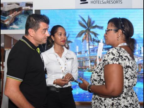 Princess Hotels & Resorts’ Marc Pelfort, regional director, sales and marketing; Kareen Hall (centre), sales and marketing director; and Michelle Gay, of American Airlines vacations, holding a discussion at their exhibition booth at the Jamaica Product E