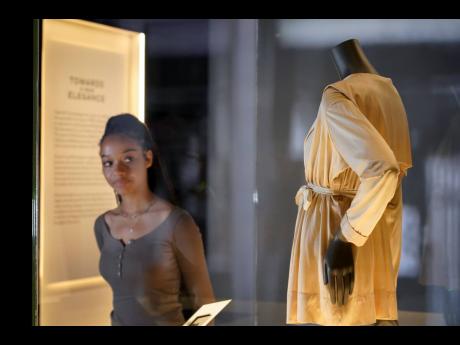 A curator poses next to a creation, which is displayed as part of the “Gabrielle Chanel. Fashion Manifesto” exhibition.