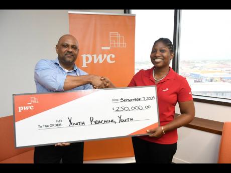 Carolyn Bell-Wisdom (right), partner and sustainability leader at PwC Jamaica, happily presents a symbolic cheque for $250,000 to Cortez Nerahoo, sixth-form coordinator at Youth Reaching Youth (YRY) on Thursday, September 7, at the Kingston office of PwC J