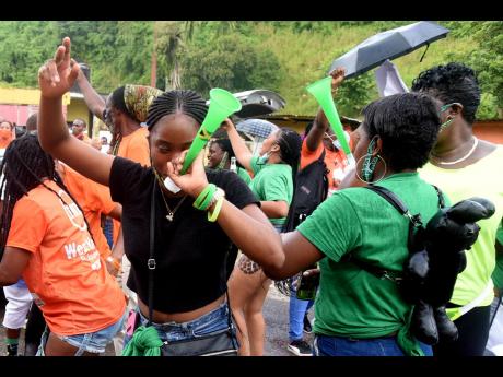 Two Jamaica Labour Party supporters blow their vuvuzelas while their People’s National Party counterparts celebrate at the Mannings Hill Primary School  in West Rural St Andrew.