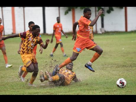 Credit: Ian Allen Chevaughn Brown (right) of Haile Selassie High evades a sliding tackle by Denham Town High’s Jordan Henry during their Manning Cup football match at the Edward Seaga Sports Complex yesterday.