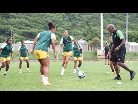 Lorne Donaldson (right), head coach, the Reggae Girlz, gets involved in a passing drill with members of the team during their final training session before their 2-0 Olympic Games qualifier loss to Canada at the National Stadium on Friday.