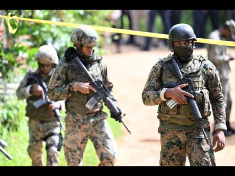 Jamaica Defence Force soldiers on the scene of a quadruple murder in Crawle, Riversdale in St Catherine yesterday.