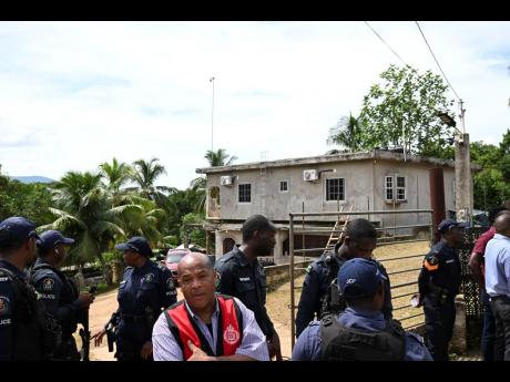 Police personnel gather at the gate to the residence where the killing occurred. 