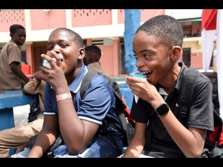 Two students from Calabar Infant and Primary school in central Kingston enjoy snow cones in the sweltering heat during Scotiabank Foundation 2023 back-to-school treat for grade 6 students at the school earlier this month.