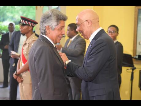 Governor General Sir Patrick Allen (right), awards the Medal of Honour to businessman Kenny Benjamin for outstanding contribution to the public service and community service, at the awards ceremony.