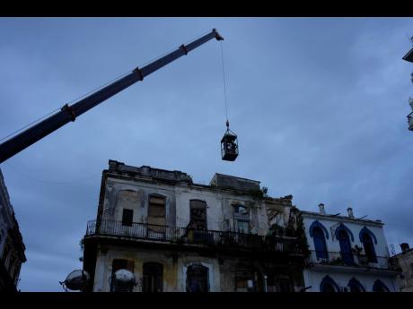 Yesterday a crane lifts firefighters in a cage toward a building in search of survivors after it partially collapsed in Havana, Cuba.