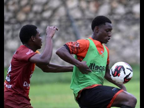 Credit: Ricardo Makyn/Chief Photo Editor Spanish Town High’s Renaldo Guy (left) stays close to Tivoli High’s Shacquwell Henry during yesterday’s ISSA/WATA Manning Cup match at the Spanish Town Prison Oval. Tivoli won 4-0.