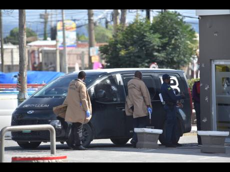 Credit: Nicholas Nunes/Photographer Police investigators process a crime scene in Harbour View, St Andrew, on Tuesday after a Beryllium cash-in-transit team was attacked by gunmen. No cash was reportedly stolen.