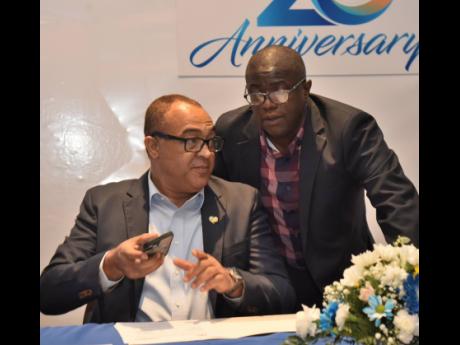 National Health Fund CEO Everton McFarlane (right) consults with Minister of Health & Wellness Dr Christopher Tufton during the award of $27 billion in drug-procurement contracts to private-sector companies on August 15, 2013 at The Jamaica Pegasus Hotel i