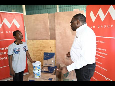 Ackeef Nugent (left), Cockburn Pen community youth teacher, is captured expressing his gratitude to Michael Howard, CEO, VM Money Transfer Services Limited, following the handing over of $100,000 worth of construction materials, including doors, paints, ce