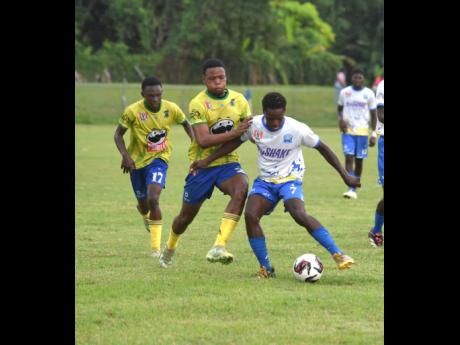 Rusea’s High School’s Corey Palmer (left) and teammate Davvaun Gibbon (centre) try to win the ball off Christiana High School’s Nickarie Foster during their ISSA/WATA daCosta Cup match at the Collin Miller Sports Complex in Lucea yesterday. 