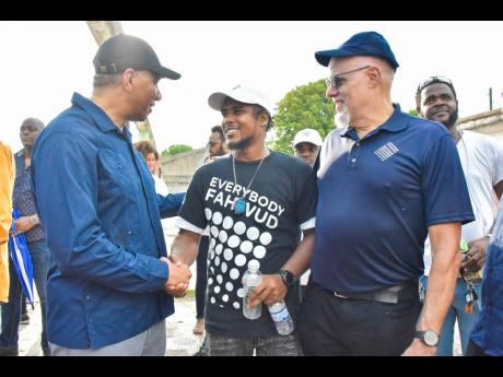 Prime Minister Andrew Holness (left) greets participant in the Project STAR (Social Transformation and Renewal) initiative, Akeem Tate  (centre), during a tour of Parade Gardens in downtown Kingston recently. They are joined by Project STAR co-chair and sp