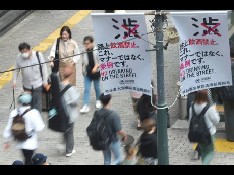 Public notice banners from Shibuya district, which read in Japanese “No Drinking on the Street” are seen near the Shibuya pedestrian crossing in Tokyo. 