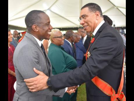 Prime Minister Andrew Holness (right) congratulates entertainer Wayne ‘Wayne Marshall’ Mitchell, who was conferred with the Order of Distinction in the rank of Officer, for contribution to the field of entertainment, in particular reggae music. The occ