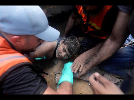 Palestinians try to rescue a boy from under the rubble of a destroyed building following an Israeli airstrike in Khan Younis refugee camp, southern Gaza Strip, yesterday.