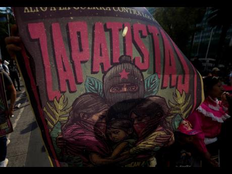 FILE - A supporter of the Zapatista Army of National Liberation, EZLN, holds up a poster whose Zapatista Mayan community was allegedly shot at by paramilitaries, during a march against the recent wave of violence that shook the Mexican state of Chiapas, in
