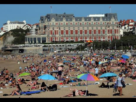 People sunbathe on Biarritz’ beach, southwestern France, on October 7. October was the fifth straight month that Earth set a record for the hottest month in recorded history.