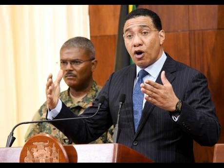 Credit: Rudolph Brown Prime Minister Andrew Holness (right) speaks to the media while Brigadier Markland Lloyd, force executive officer of the Jamaica Defence Force, looks on during a post-Cabinet press briefing at Jamaica House yesterday.