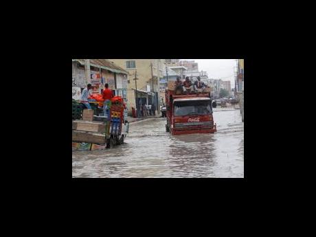 Credit: AP Vehicles try to manoeuvre through flood water caused by heavy rain, in Mogadishu.