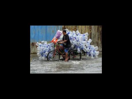 Credit: AP A man uses his pedicab to transport used plastic containers along a flooded street in Valenzuela city, Philippines, in this August photo.