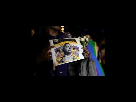 A demonstrator holds a picture of Jesus Ociel Baena in Mexico City on Monday. The first openly nonbinary person to assume a judicial position in Mexico was found dead in his home Monday in the central Mexican city of Aguascalientes after receiving death th