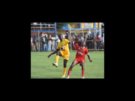 Dinthill Technical High School’s Zidane Clarke (left) and BB Coke High school’s Devonte Blake keep their eyes peeled for a dropping ball as they get ready to tussle for possession during their ISSA/WATA daCosta Cup quarter-final football match at the S
