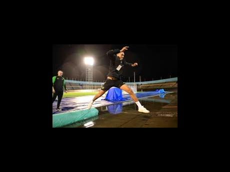 Reggae Boy John Russell leaps over water on the cycle track at the National Stadium last night.